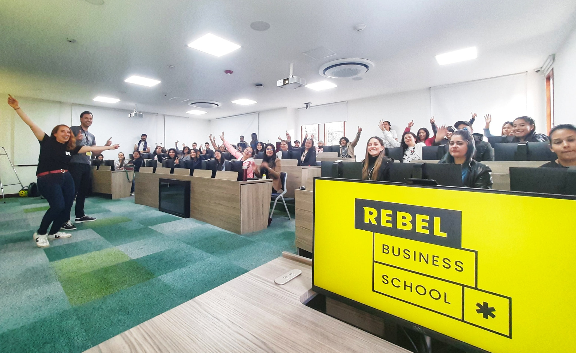 University classroom of participants raising hands during a Rebel workshop